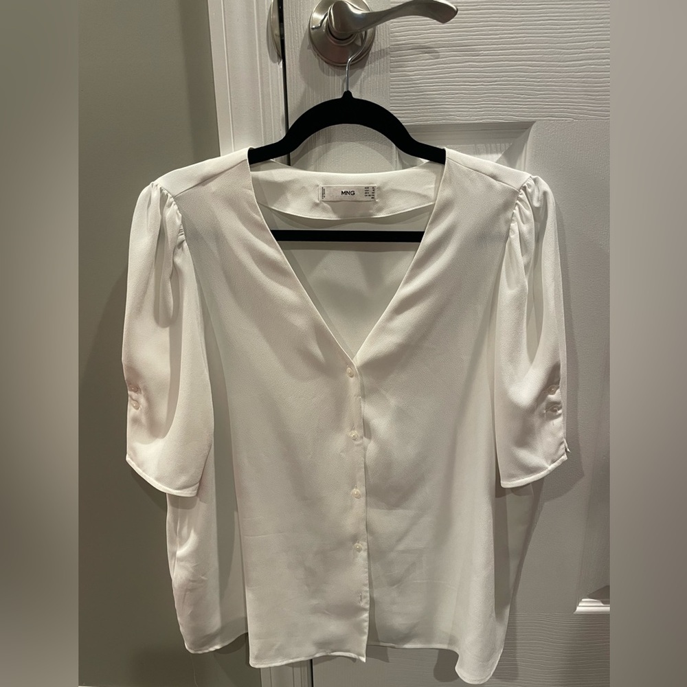 Puffed sleeve, light cream colored blouse with button on sleeve detail.